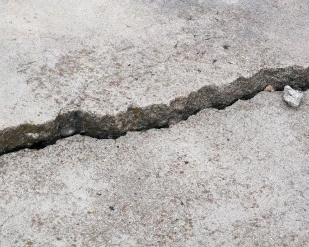Cracked concrete driveway in Lansing, MI showing sinking slab before concrete leveling services.