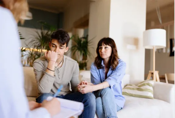 A concerned couple speaking with a doctor looking forlorn