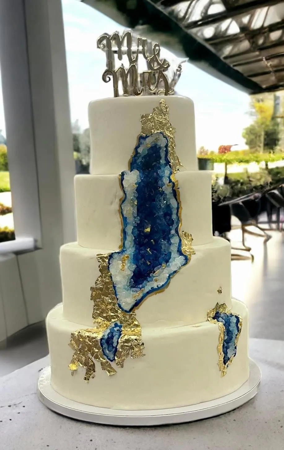 Minimal, tall wedding cake styled against a dark, moody backdrop