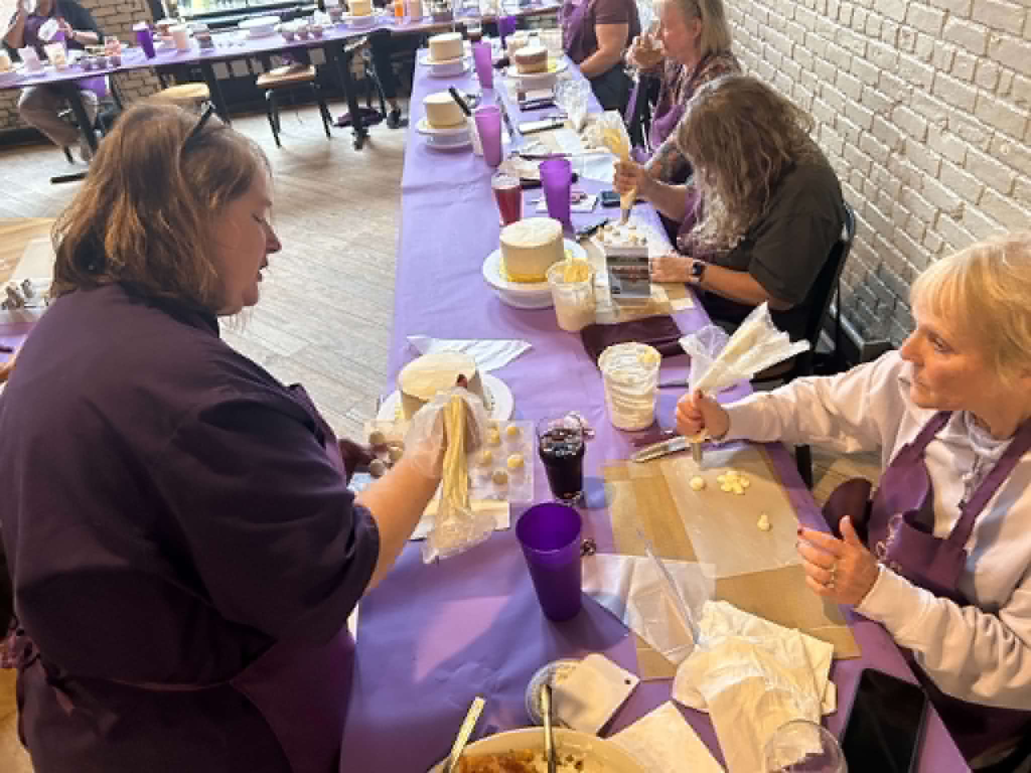 Friends raising glasses around a table of partially decorated cakes