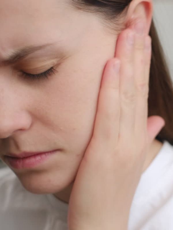 woman holding her ear in discomfort