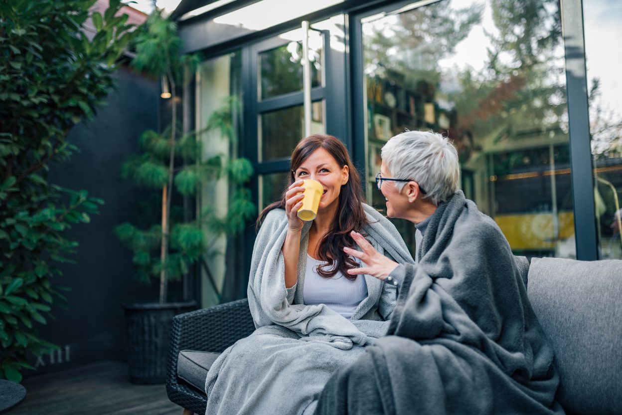 elderly mom and daughter having coffee on the porch