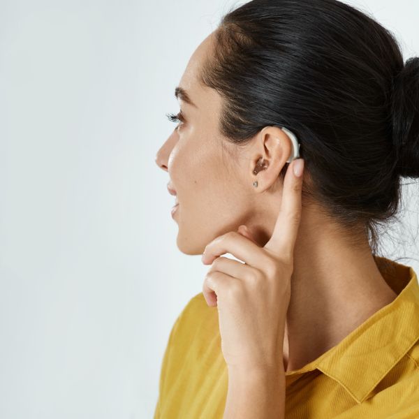 woman adjusting a hearing aid that she's wearing