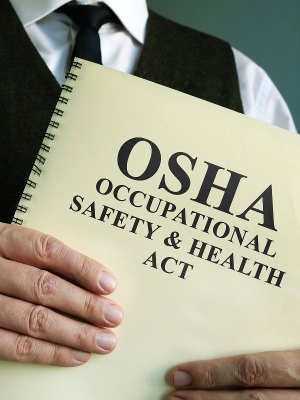 man in a suit holding the OSHA manual
