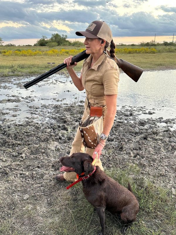 woman walking with her dog and holding her rifle over her shoulder