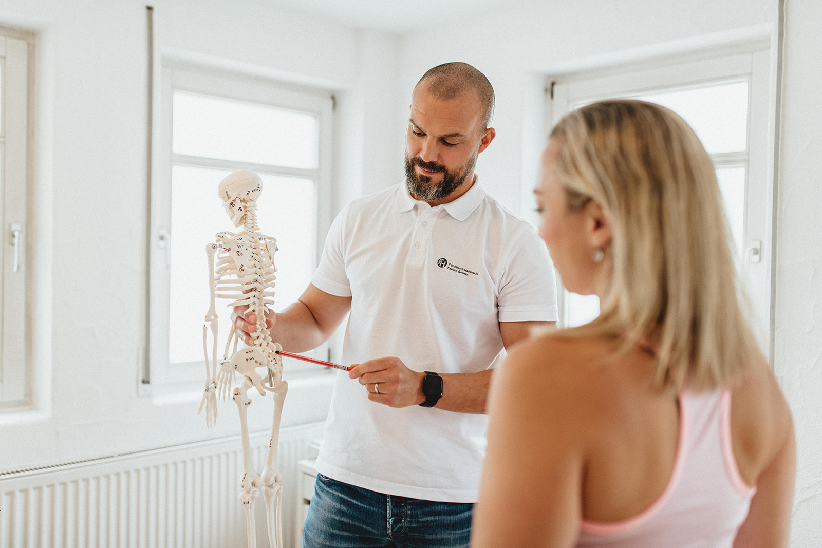 Fabian Berner erklärt einem Patienten das Erklärungsmodell seiner Beschwerden