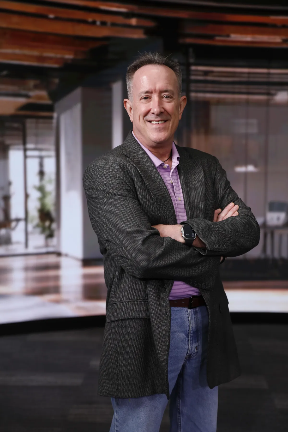 Doug Belkofer standing, smiling, with arms crossed.