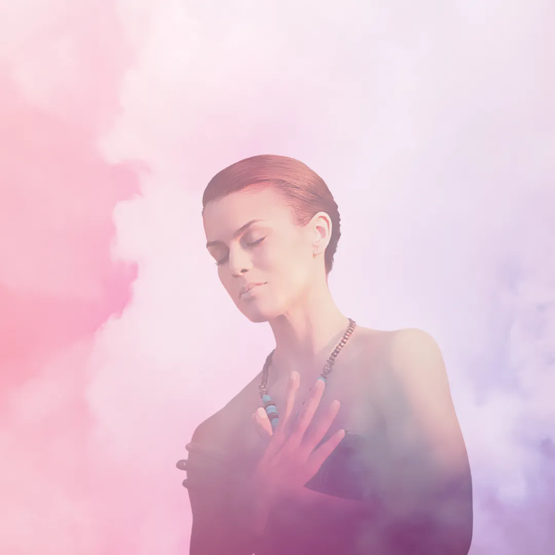 spiritual woman, surrounded in colourful clouds and spirit, touching her heart wearing torquise beads