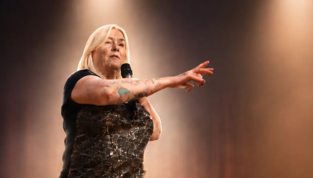 Elaine Somerville delivering a live mediumship demonstration on stage during a psychic and spiritual event with dramatic theatre lighting.