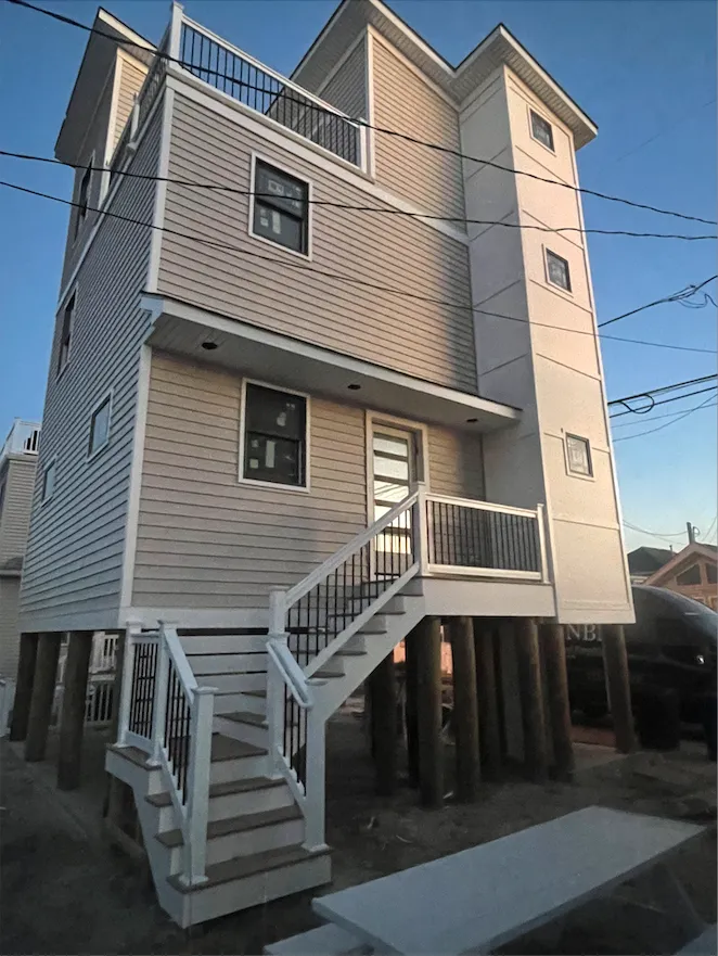 Contemporary living room with floor-to-ceiling windows, minimalist furniture, and a family playing board games. The room is filled with sunlight, featuring neutral colors and subtle decorative accents.
