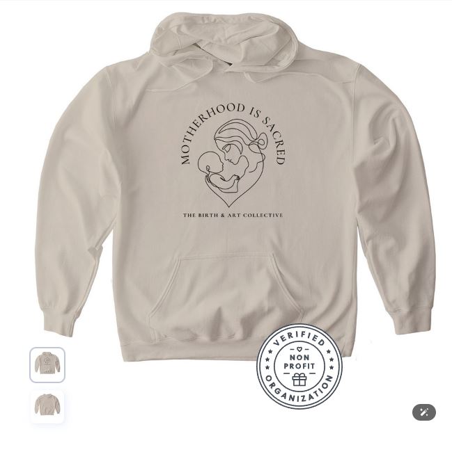 Motherhood Is Sacred beige hoodie by The Birth & Art Collective featuring a minimalist mother and baby line drawing, sold to support the nonprofit’s mission.