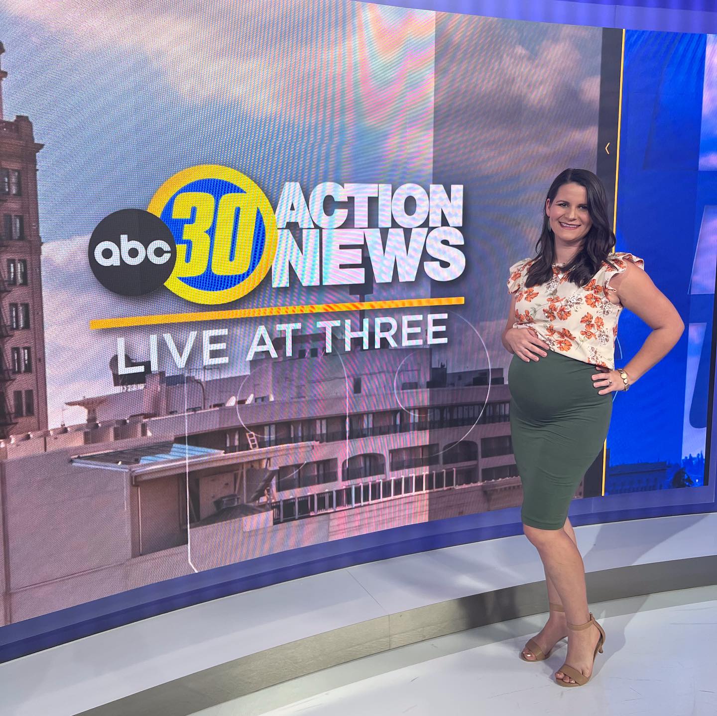 Founder of The Central Valley Belly to baby Expo and The Birth & Art Collecive posing in front of the ABC 30 Action News Screen after an in-studio interiew