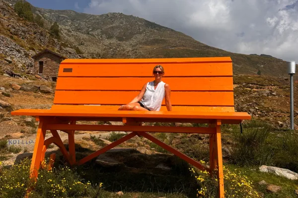 Johanna Urquhart, leadership coach and founder of Resta Forte, sitting on the giant orange bench at Andrate in Piemonte, Italy