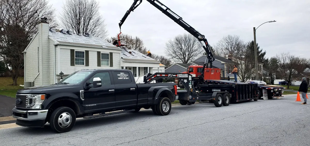 a group of expert roofers on the job with the dumpster truck