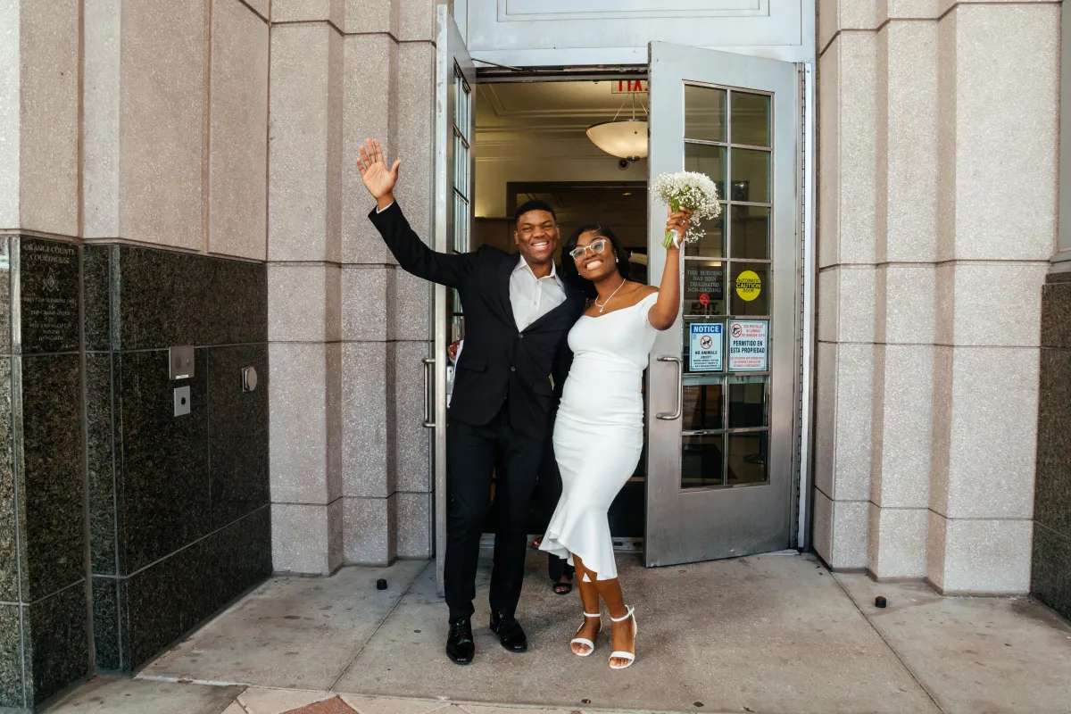 Excited couple exits courthouse after their joyful marriage ceremony