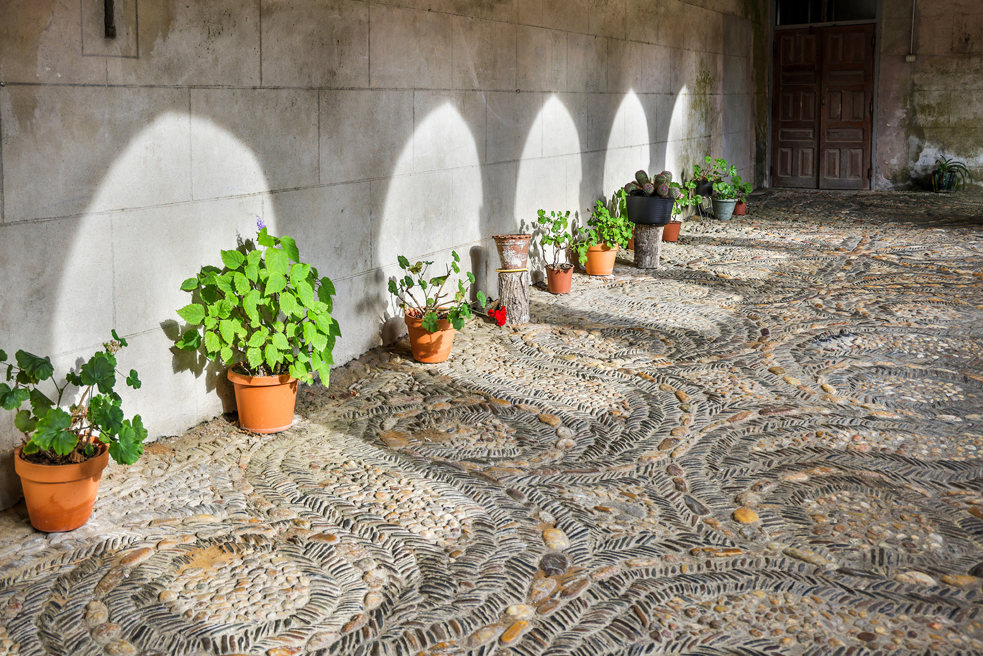 Pebbled cloister walkway with potted plants at the Monastery of the Magdalena in Sarria