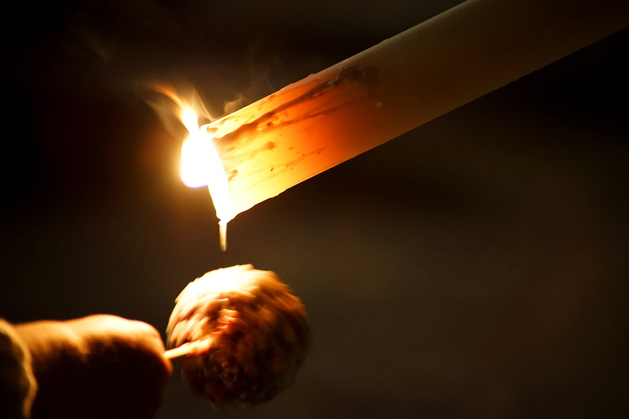 Hand holding a wax ball beneath a candle during a Semana Santa procession