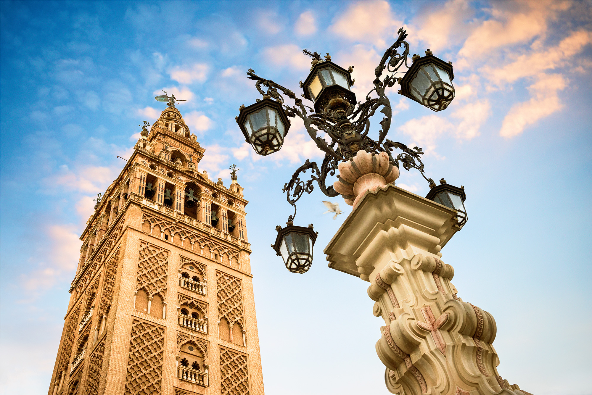 The Giralda bell tower of Seville Cathedral with an ornate street lamp in the foreground
