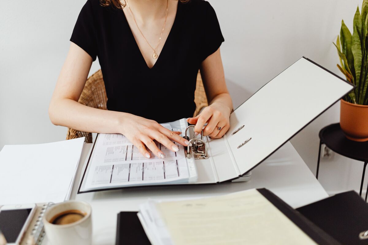 Person working through a binder of financial documents at a desk with a cup of coffee