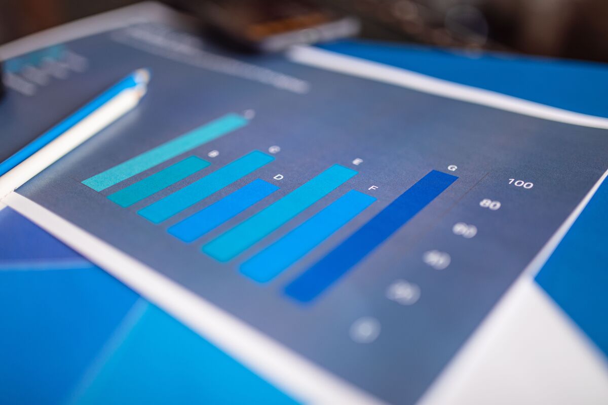 Printed blue bar chart with mostly even bars on a desk beside a pencil