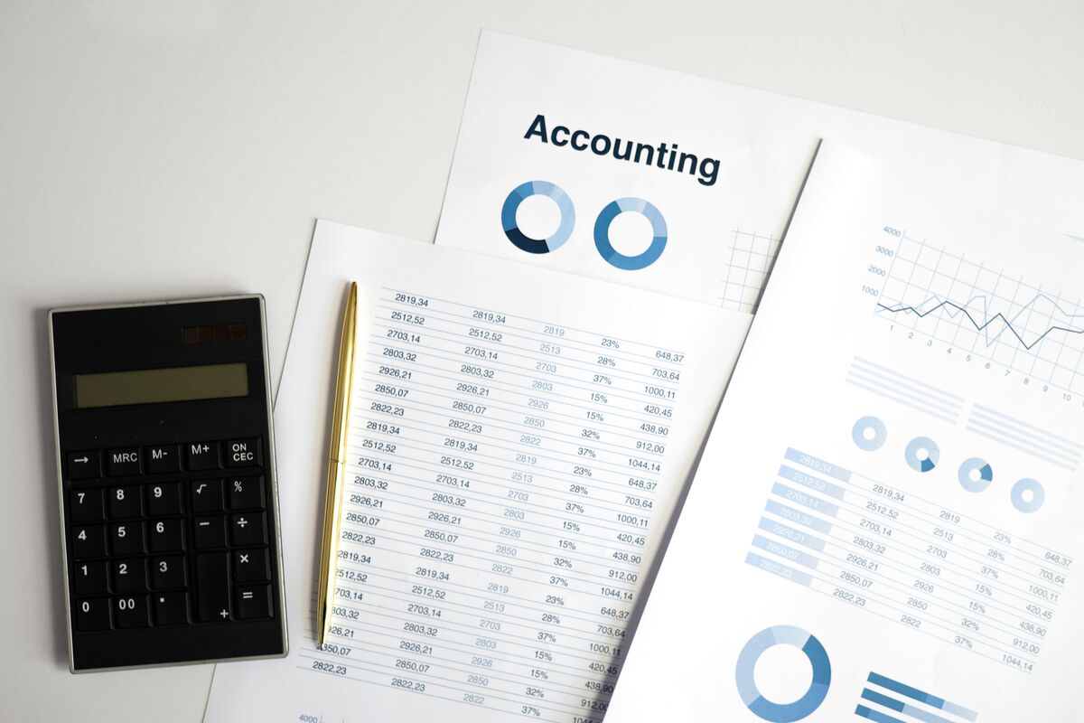 Printed accounting report with columns of figures, donut charts and a calculator on a desk