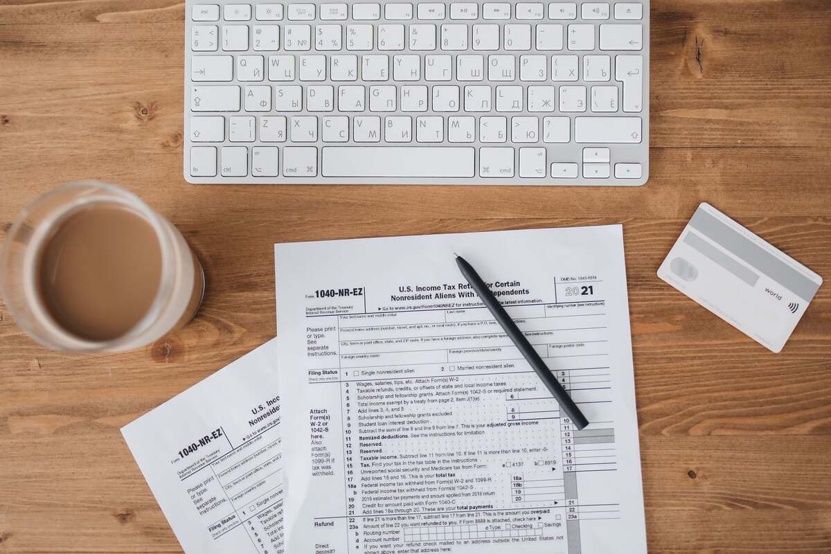 U.S. income tax return form on a wooden desk beside a keyboard, pen and a cup of coffee