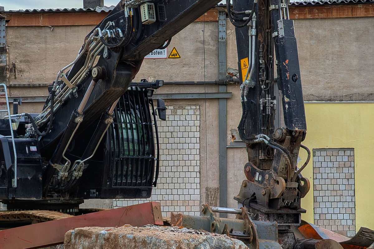 Close-up of a tracked excavator arm and grapple at a demolition and construction worksite