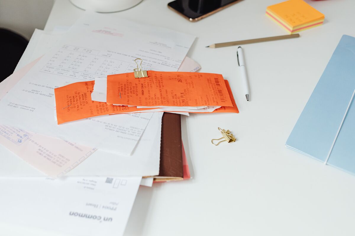 Receipts clipped together with paper documents, envelopes and sticky notes spread across a white desk for tax season
