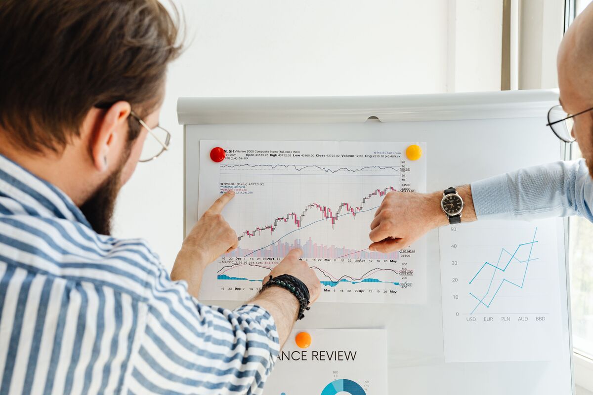 Two professionals reviewing financial growth charts and trend graphs pinned to a whiteboard during a review