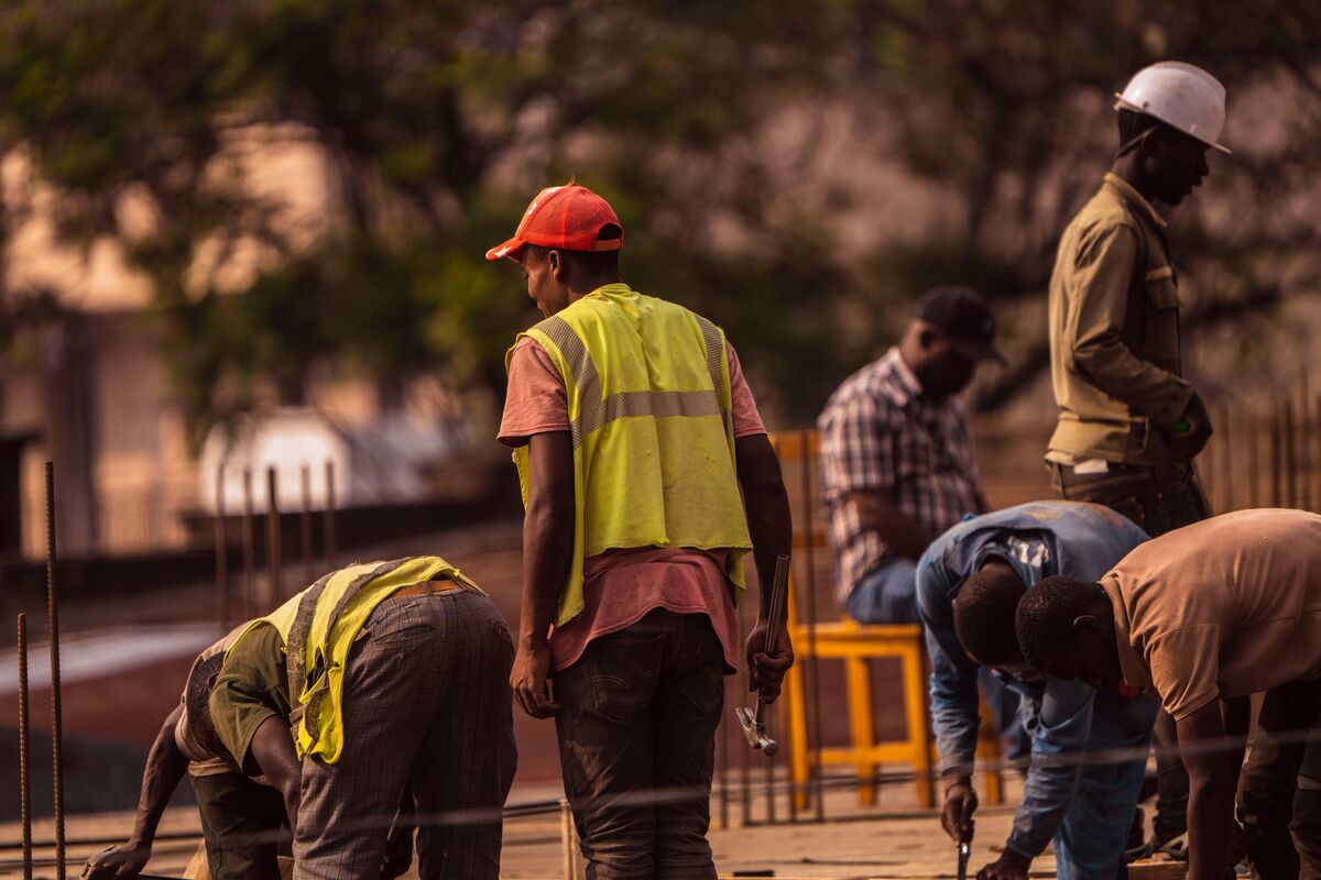 Construction crew in high-visibility vests and a hard hat working together on a building site at dusk