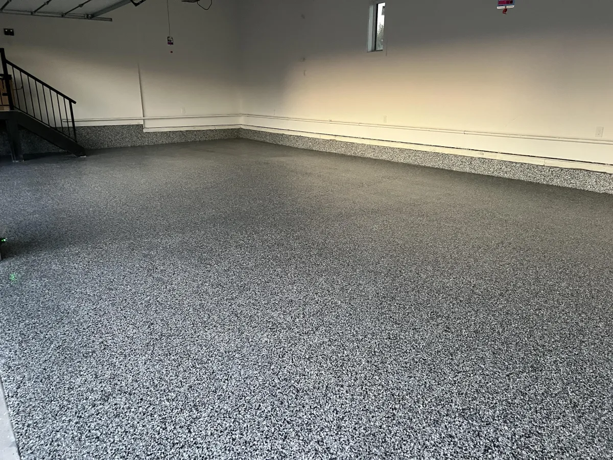 Empty commercial space with full-coverage dark grey epoxy flake flooring