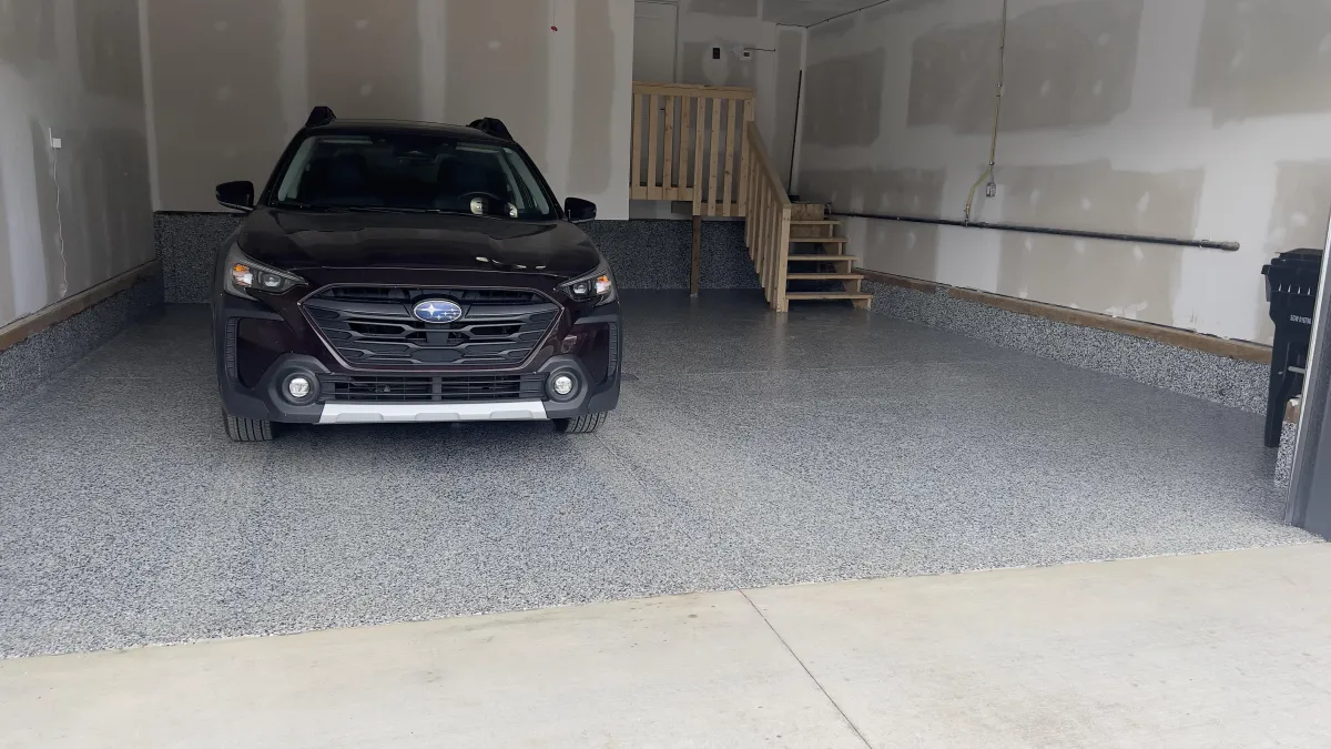 Residential garage with clean grey flake epoxy floor and parked SUV