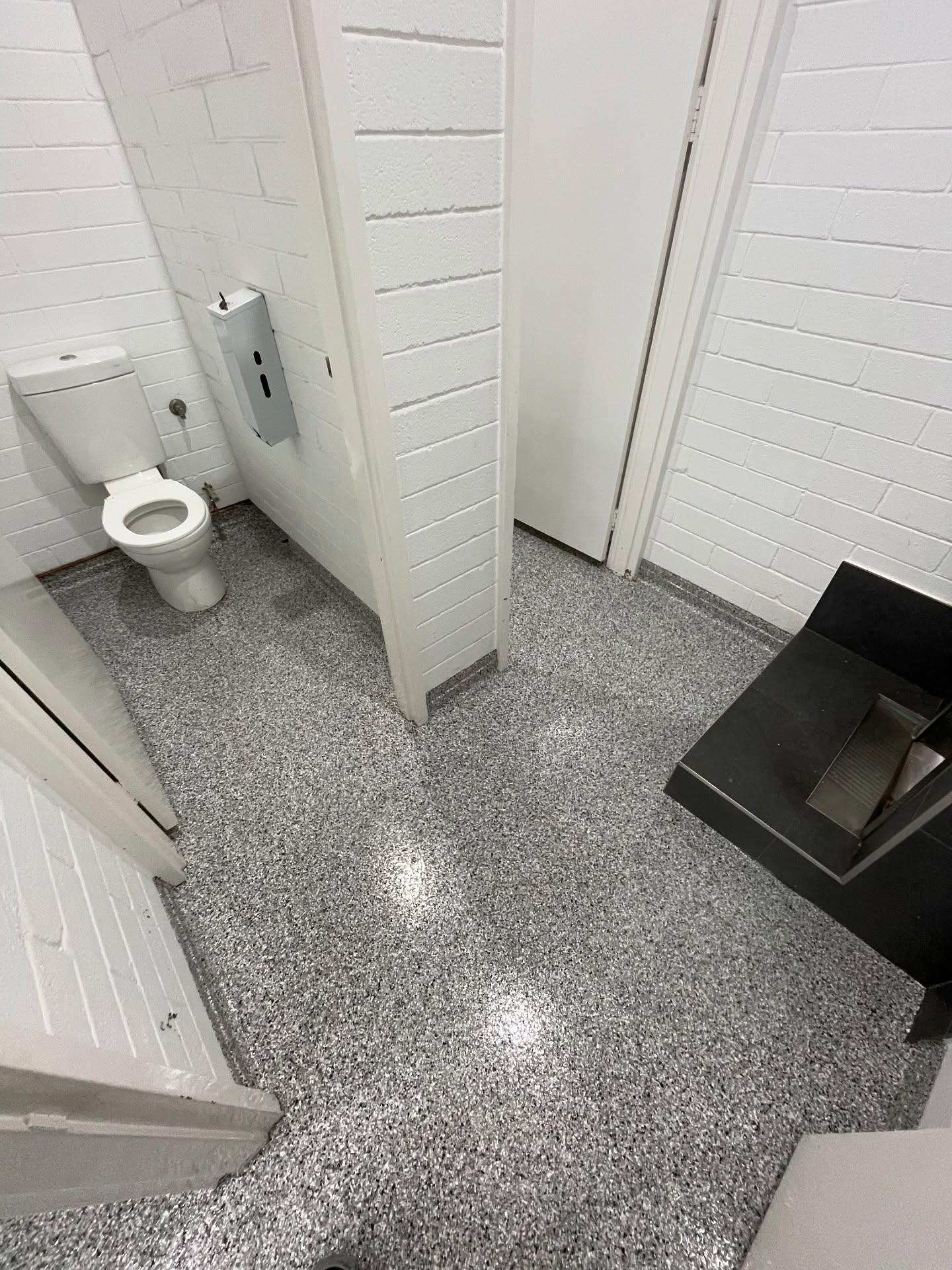 Commercial washroom with seamless epoxy flake flooring extended up baseboards