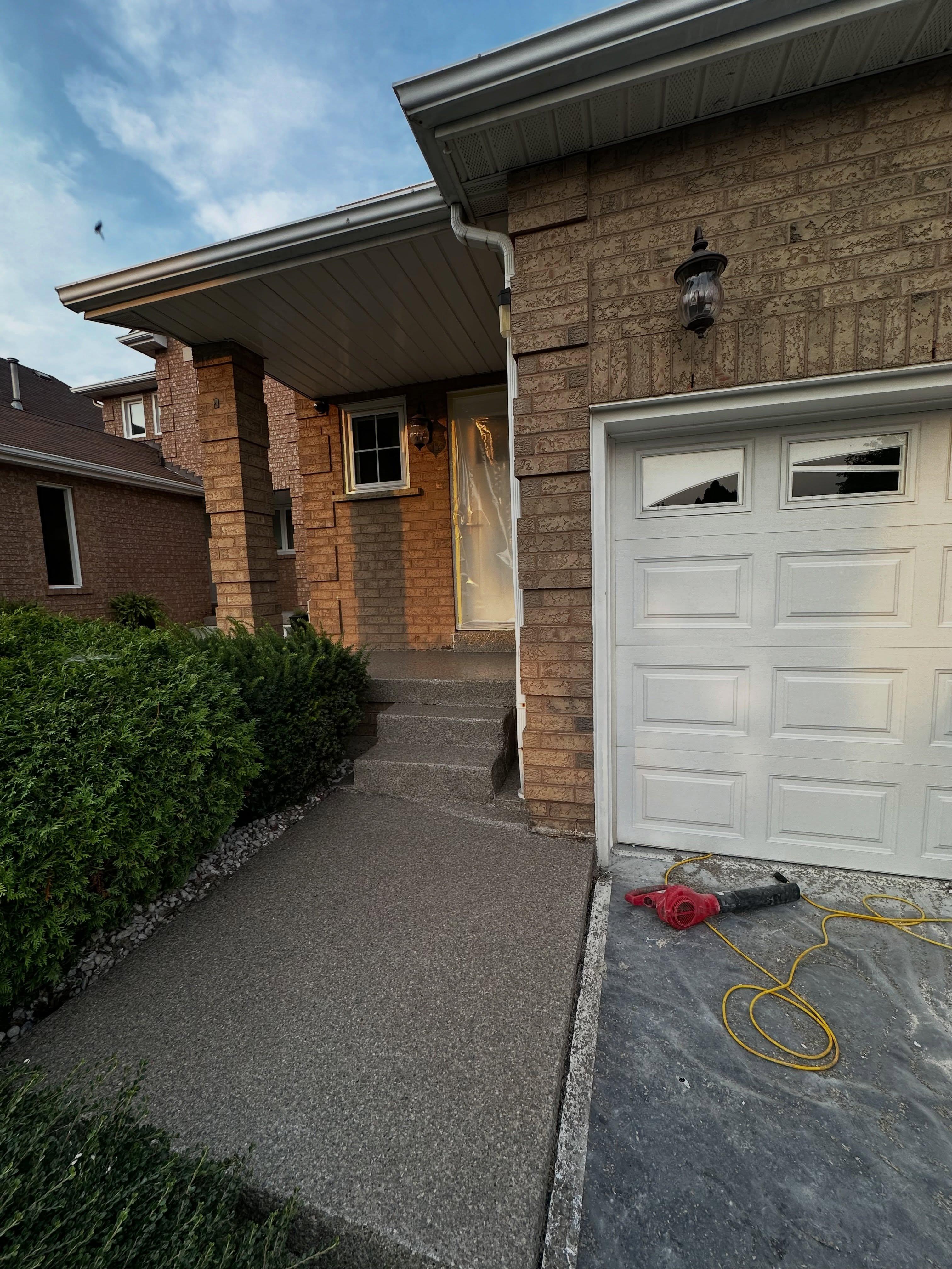 Residential entryway and garage exterior with concrete sealing treatment