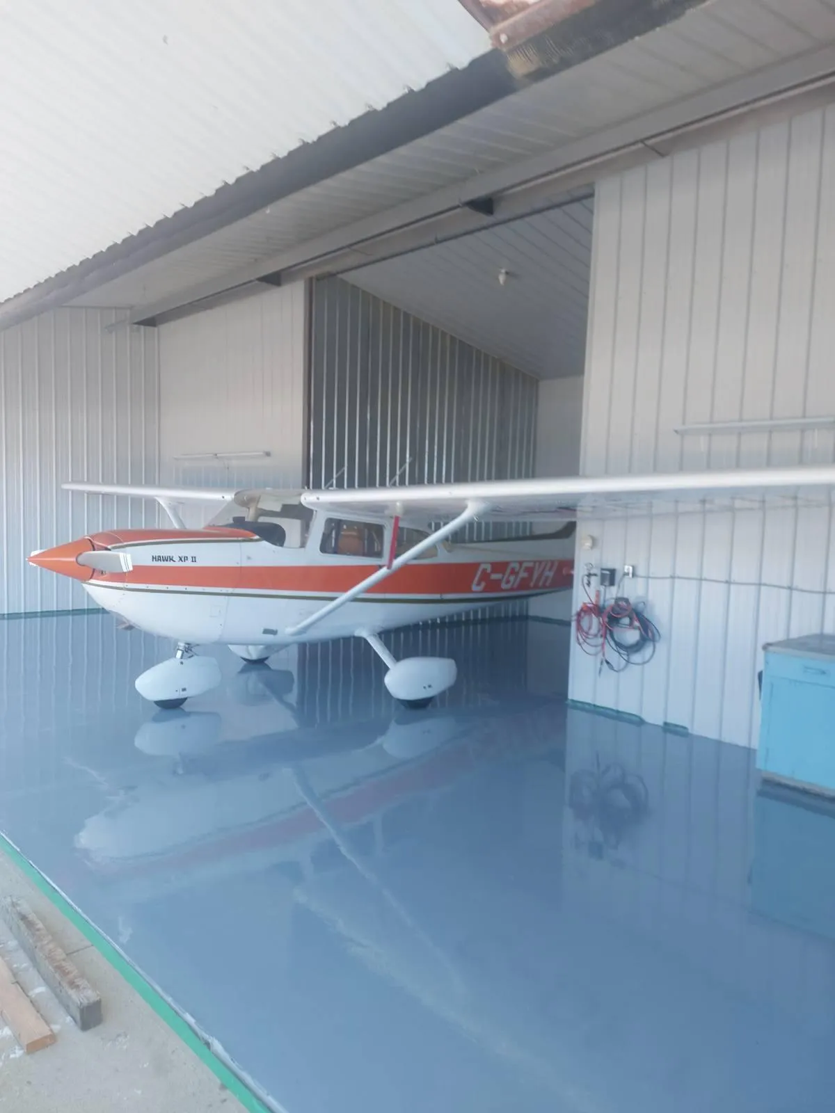 Aircraft hangar bay with reflective light blue epoxy floor coating and small airplane