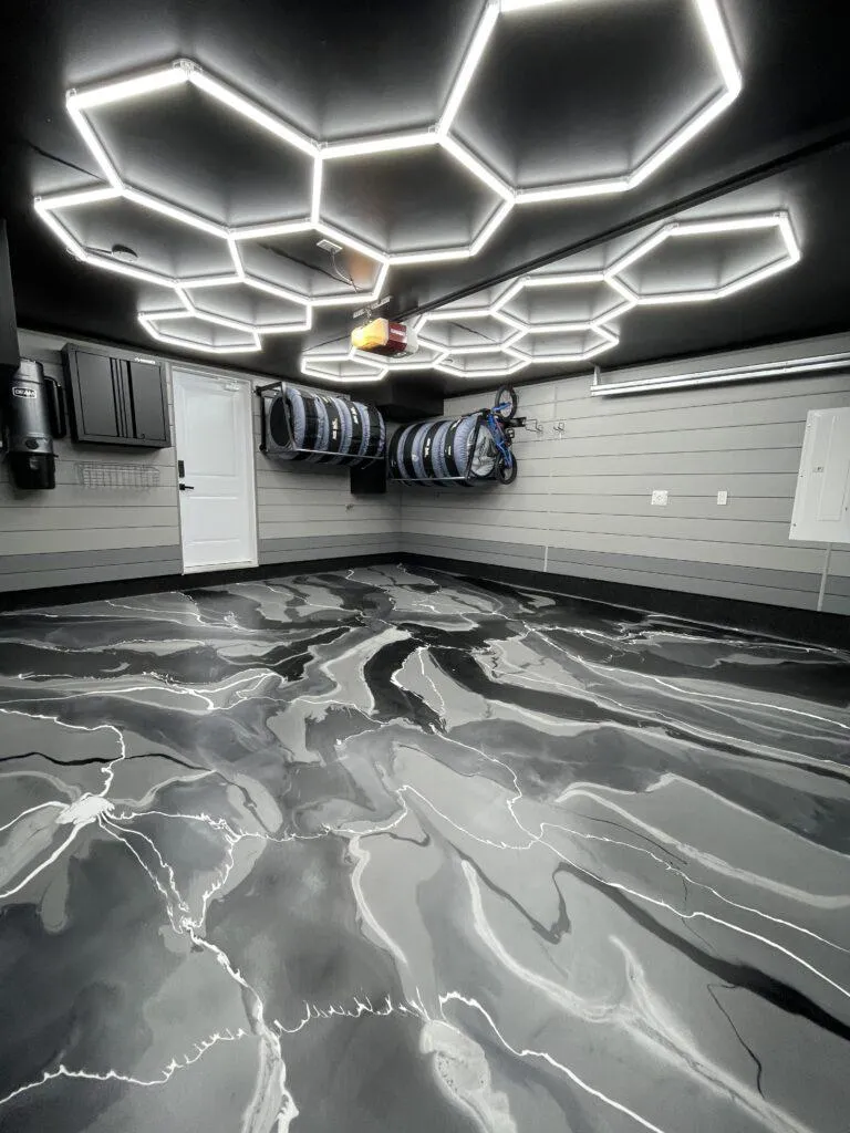 Modern garage space with dark metallic epoxy flooring and overhead hexagonal LED lights