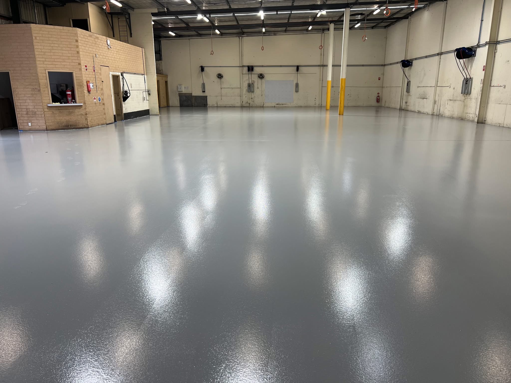 Large empty industrial facility with high-gloss grey commercial epoxy floor