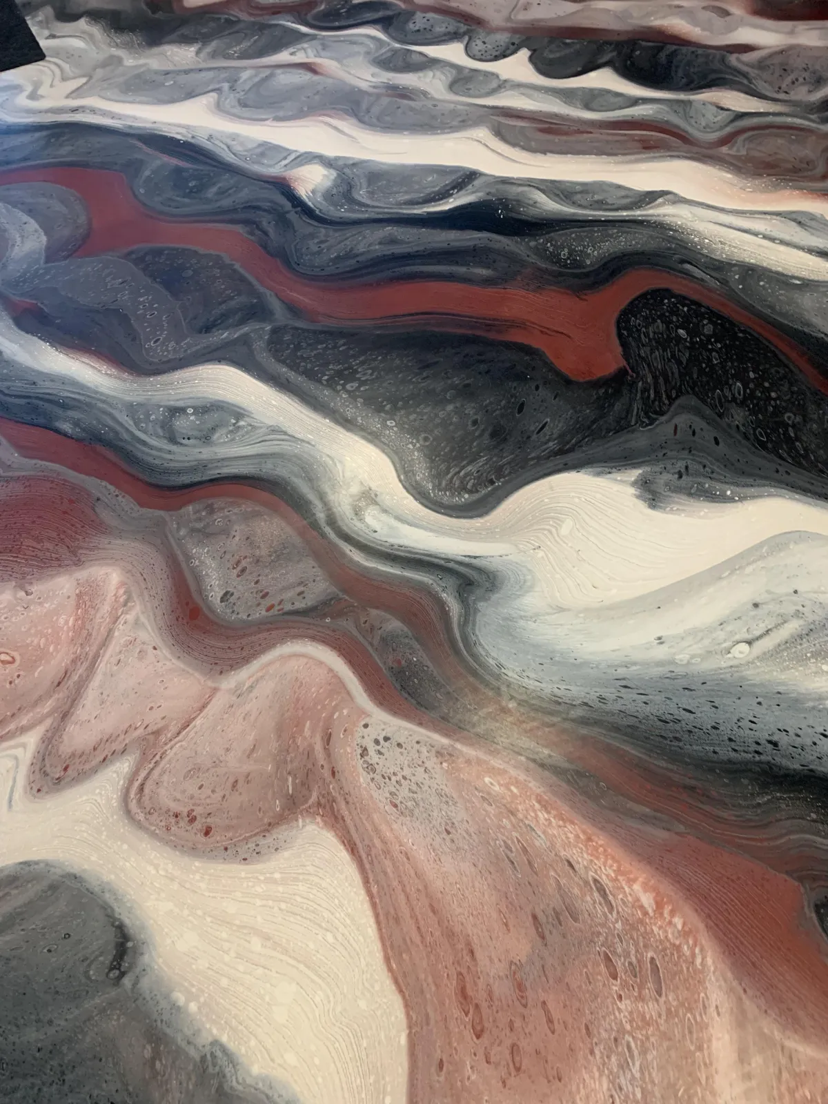 Close up detail of custom metallic epoxy floor with red silver and charcoal swirls