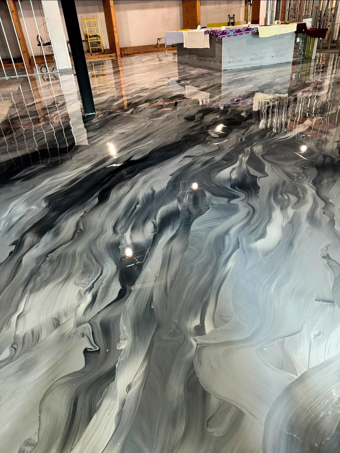 Custom metallic epoxy floor featuring dynamic black grey and white marble swirl patterns