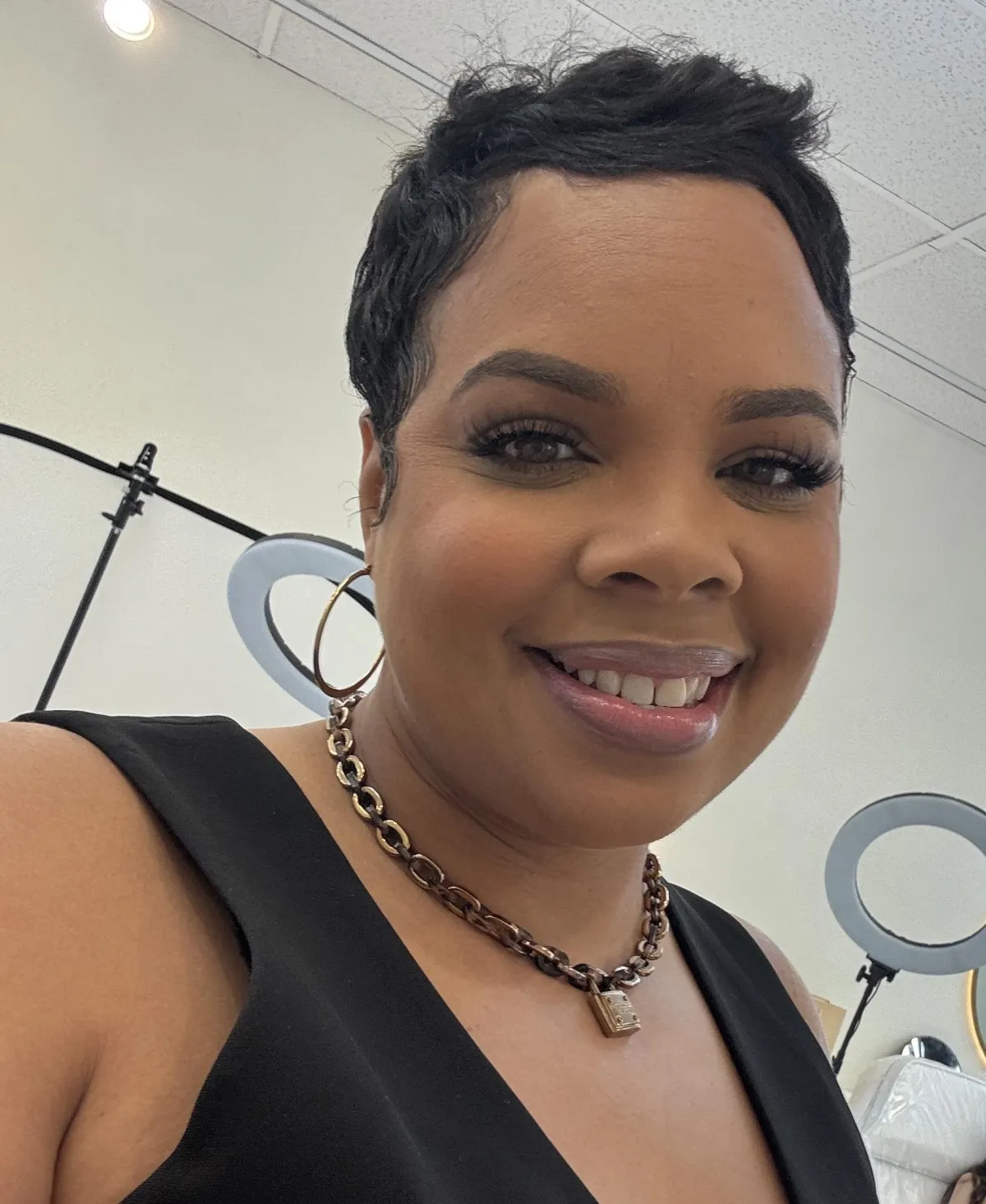 Ash, founder of Enhanced by Ash, in a modern studio, smiling confidently