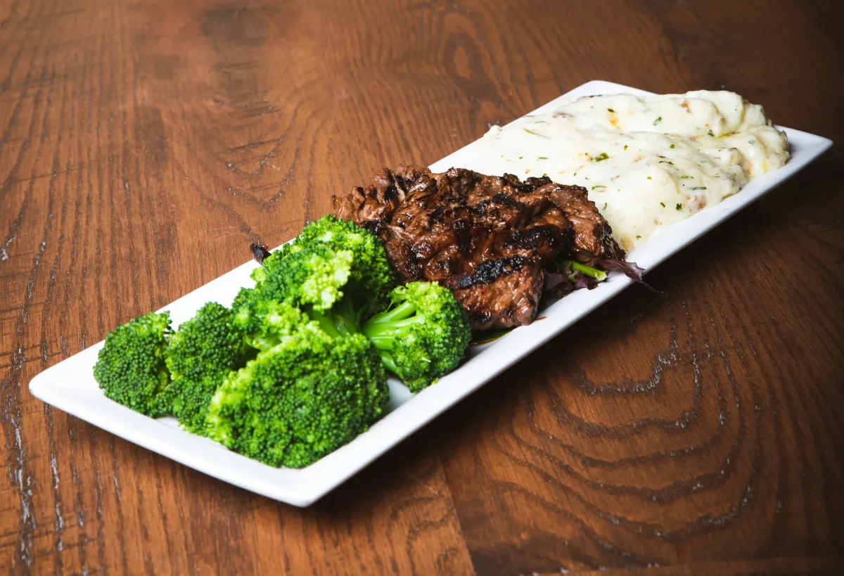 A plate with marinated steak tips sided with broccoli and mashed potatoes