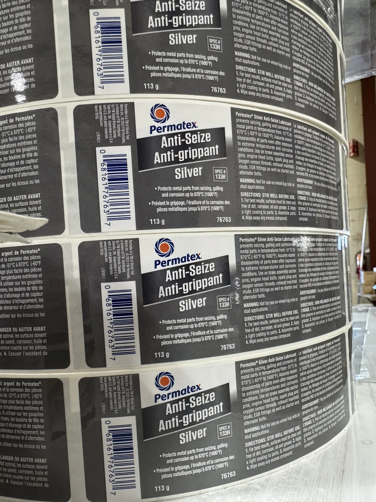 Multiple finished rolls of professionally printed product labels stacked neatly on a pallet or production table in a clean label manufacturing environment, showing repeat production (generic unbranded designs).