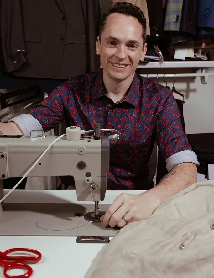 A man in a black suit loosening his tie
