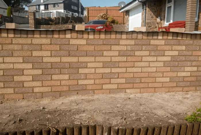 A newly built light red brick front garden wall