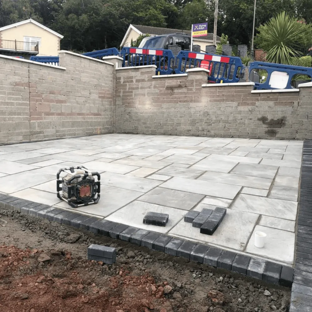 A light grey patio with dark grey brick border in Blackwood
