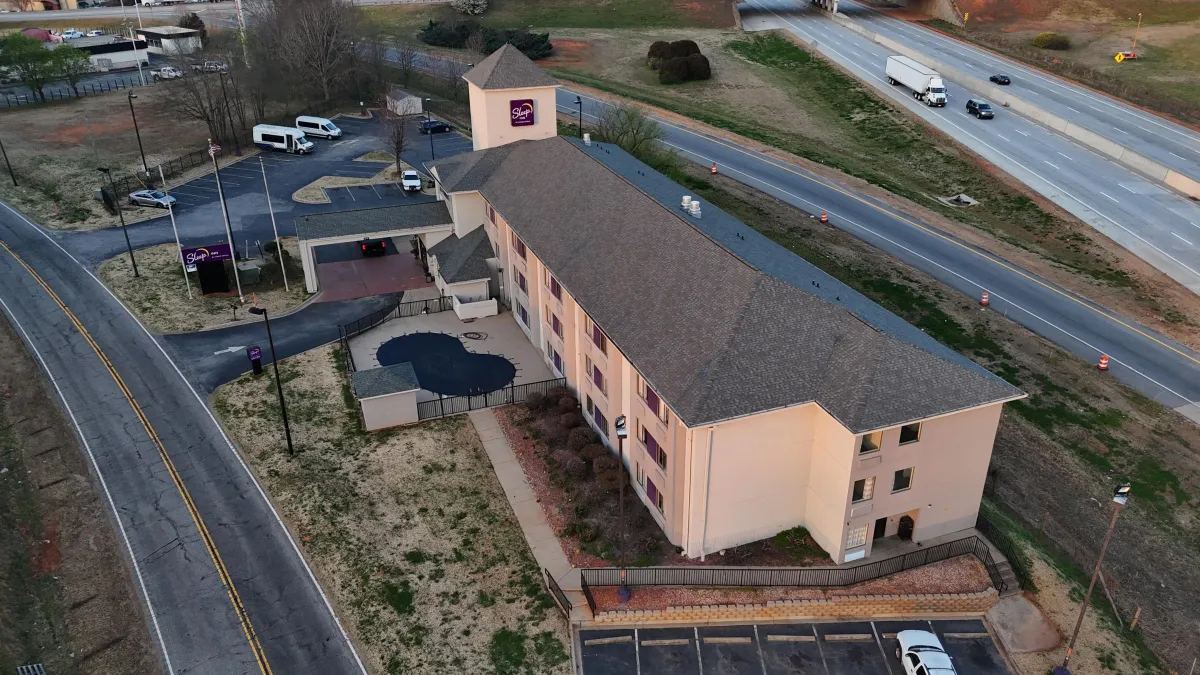 Upscale multi-story hotel featuring a comprehensive architectural shingle roof system with specialized high-traffic design elements, showcasing Your Neighbor's Contractor's commercial roofing expertise for hospitality properties where aesthetics and long-term performance are equally critical for guest satisfaction and operational efficiency.
