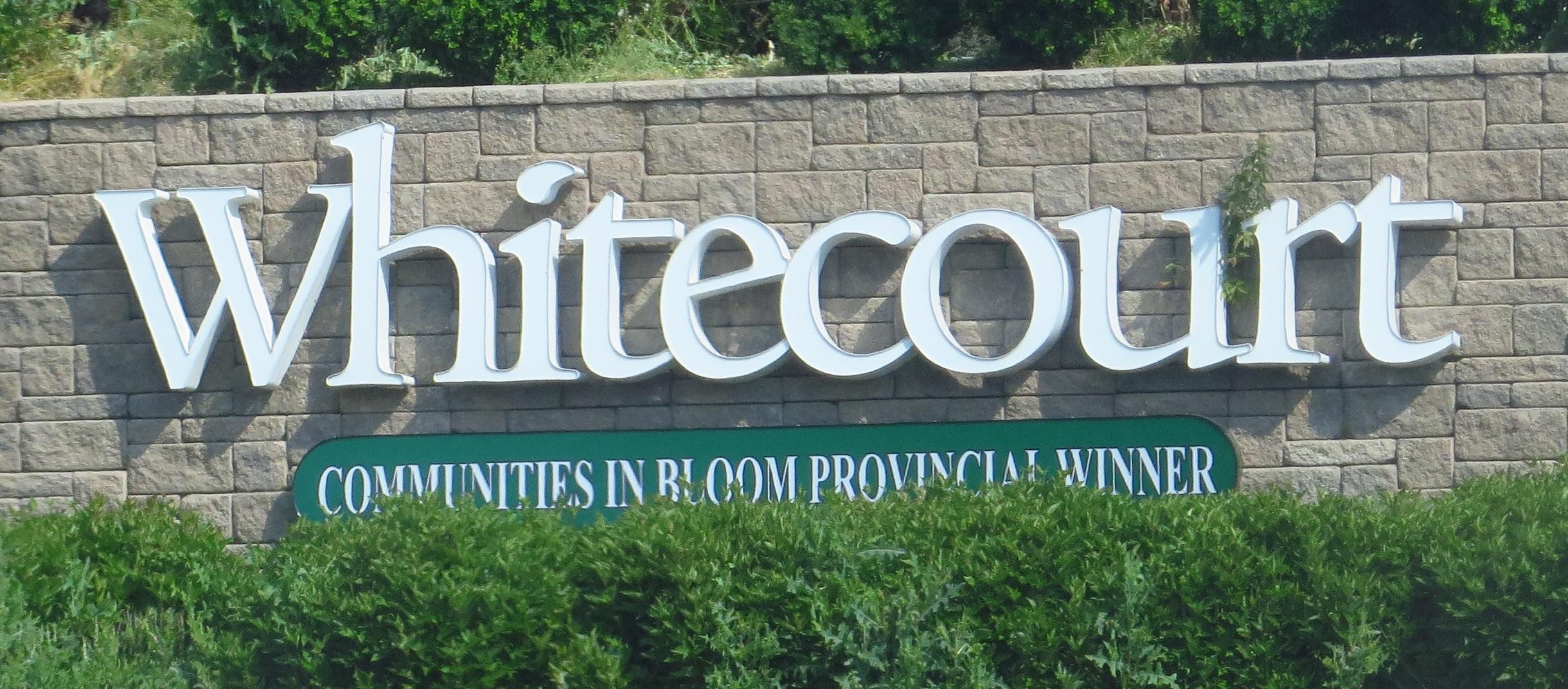 Whitecourt welcome sign surrounded by green landscaping