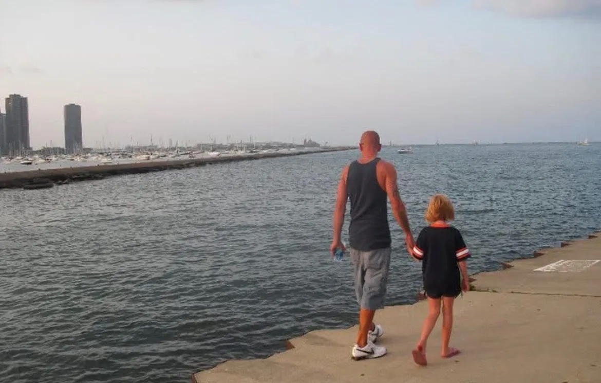 Scott and Mersades walking hand in hand beside the lake.