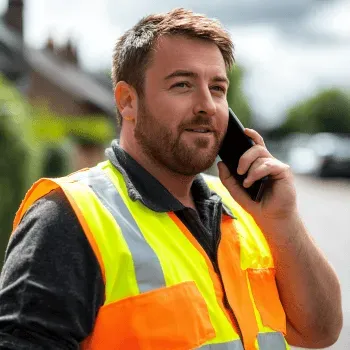 Tradesman on phone wearing high-vis vest – business owner notified of negative Google review
