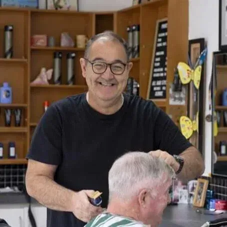 Barber cutting customer’s hair in salon with friendly service and professional setup